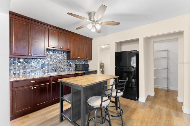 kitchen with black appliances, sink, decorative backsplash, light hardwood / wood-style floors, and butcher block counters