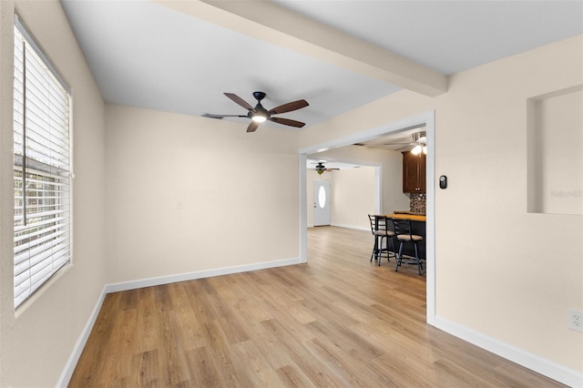 unfurnished room with beam ceiling, a healthy amount of sunlight, and light hardwood / wood-style floors