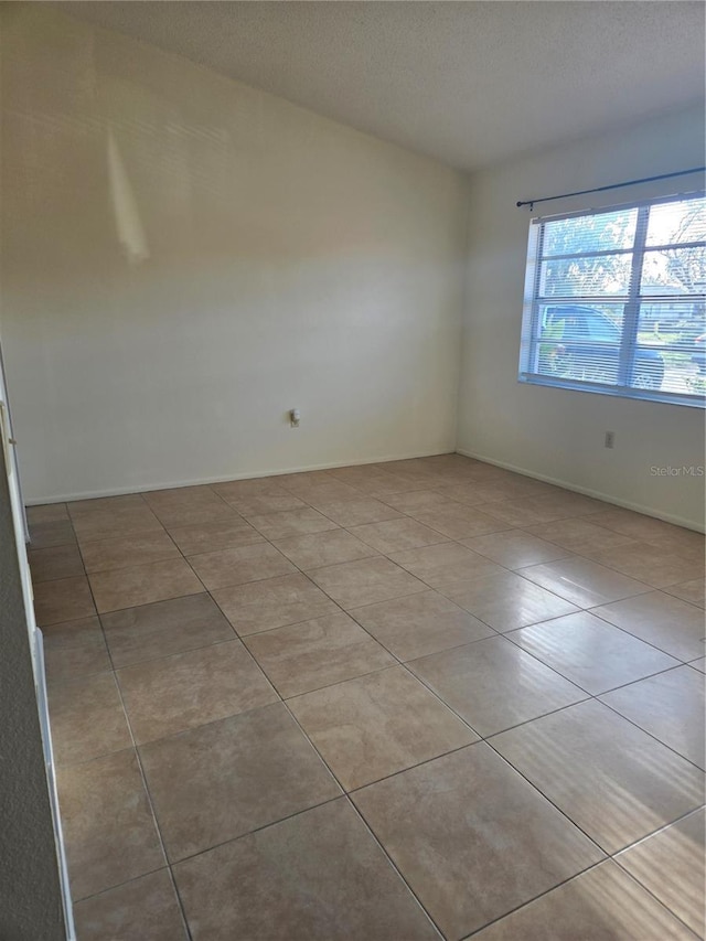 unfurnished room with light tile patterned floors and a textured ceiling