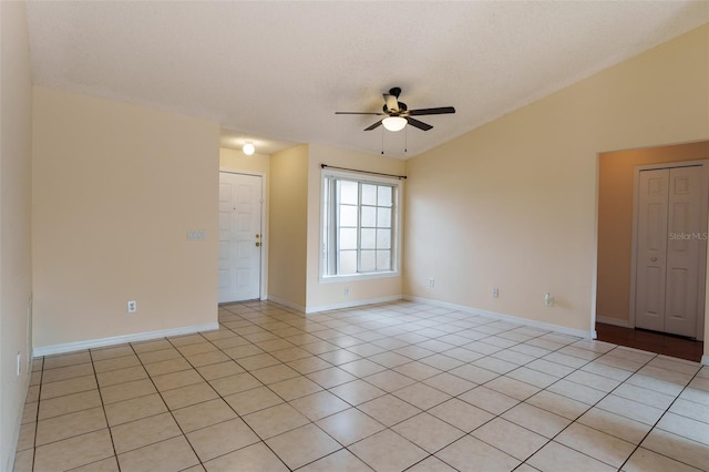 empty room featuring ceiling fan, lofted ceiling, a textured ceiling, and light tile patterned floors