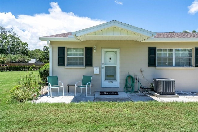 entrance to property featuring a yard and central AC unit