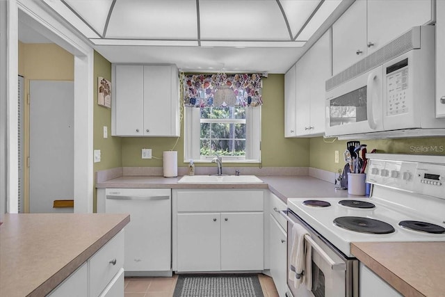 kitchen featuring white cabinetry, sink, light tile patterned floors, and white appliances