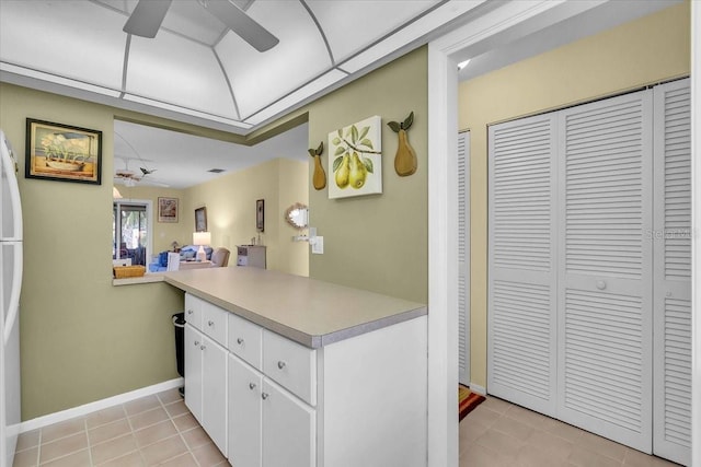 kitchen with kitchen peninsula, white cabinetry, light tile patterned flooring, and ceiling fan