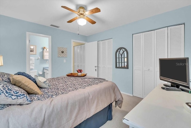 bedroom with multiple closets, ceiling fan, ensuite bathroom, and light colored carpet