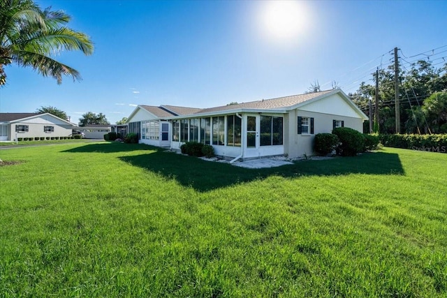 back of property featuring a lawn and a sunroom