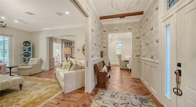 living area featuring beamed ceiling, light parquet flooring, a healthy amount of sunlight, and an inviting chandelier