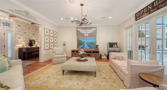 living room featuring crown molding, a chandelier, and light wood-type flooring