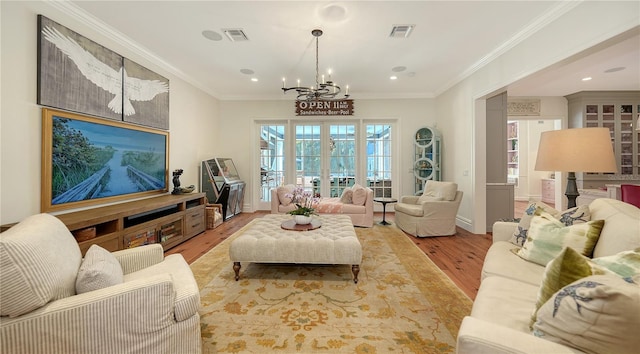 living room with a notable chandelier, crown molding, and light hardwood / wood-style floors