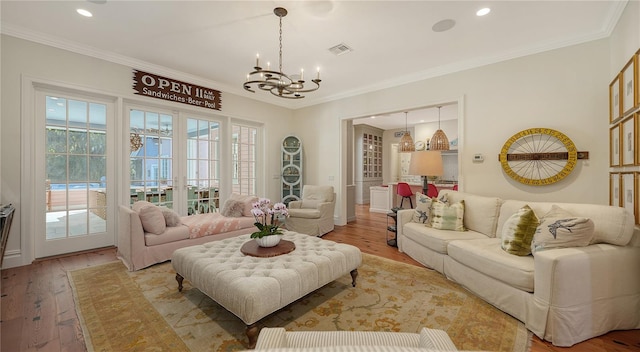 living room with ornamental molding, a chandelier, light hardwood / wood-style floors, and french doors