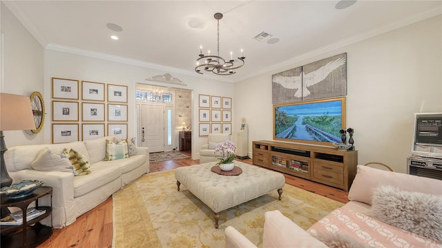 living room with a notable chandelier, ornamental molding, and light wood-type flooring