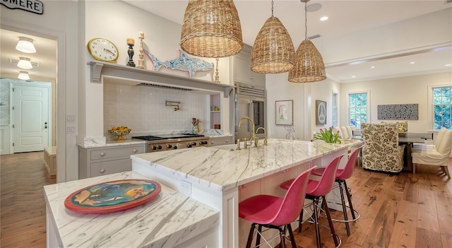 kitchen with tasteful backsplash, decorative light fixtures, a kitchen island with sink, and appliances with stainless steel finishes