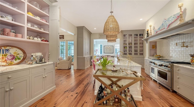 kitchen featuring light hardwood / wood-style flooring, gray cabinetry, decorative light fixtures, custom exhaust hood, and range with two ovens