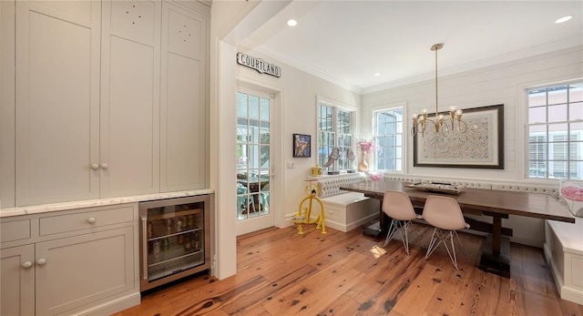 dining room featuring wine cooler, a chandelier, breakfast area, crown molding, and light hardwood / wood-style flooring