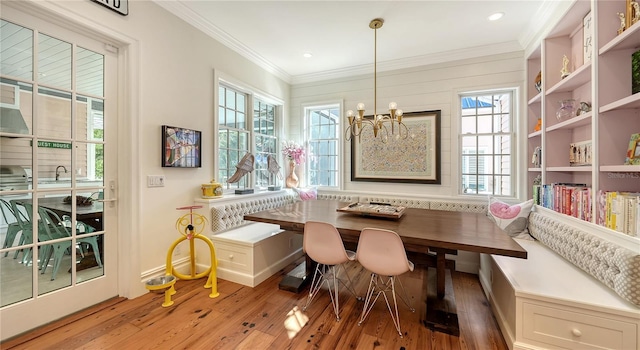 dining space with crown molding, light hardwood / wood-style flooring, a chandelier, and breakfast area