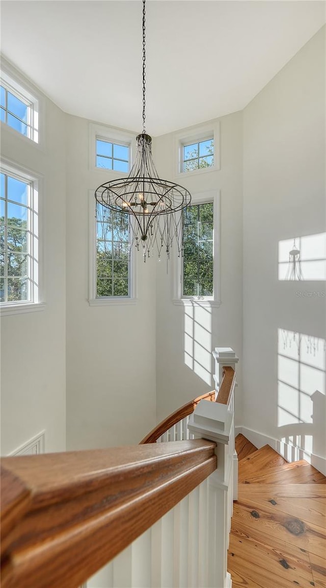 staircase featuring hardwood / wood-style flooring, a wealth of natural light, and a chandelier