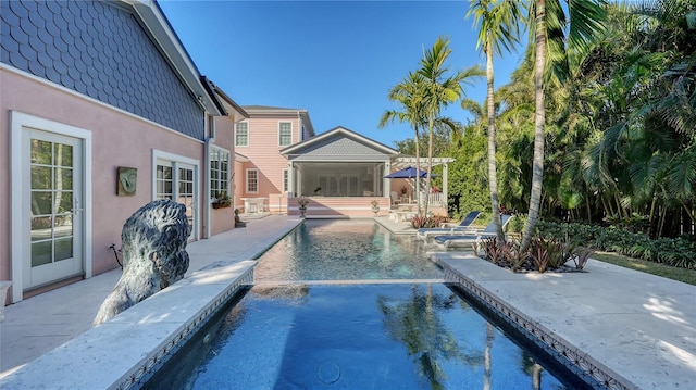 view of pool featuring pool water feature, a sunroom, and a patio area