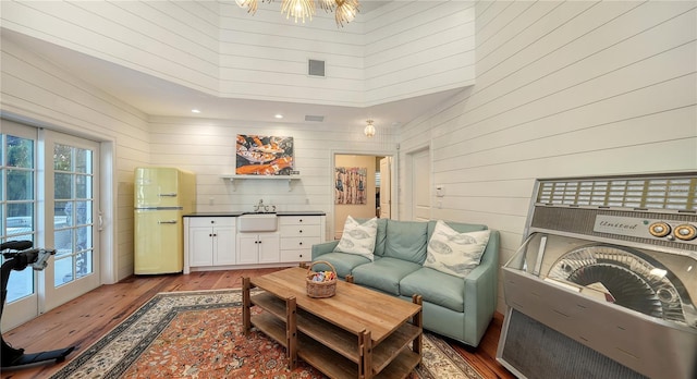 living room featuring sink, hardwood / wood-style flooring, wooden walls, and a high ceiling