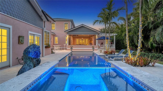 pool at dusk with a jacuzzi and a patio