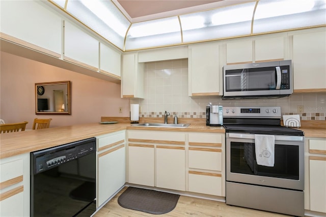 kitchen with sink, white cabinets, light wood-type flooring, kitchen peninsula, and stainless steel appliances