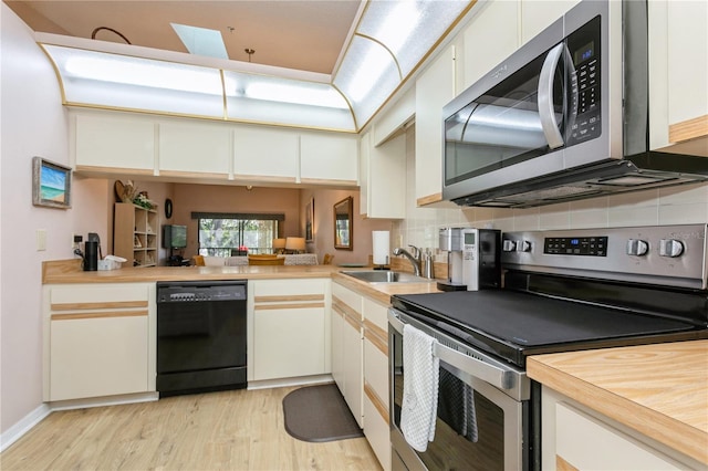 kitchen featuring white cabinets, stainless steel appliances, light hardwood / wood-style floors, sink, and kitchen peninsula