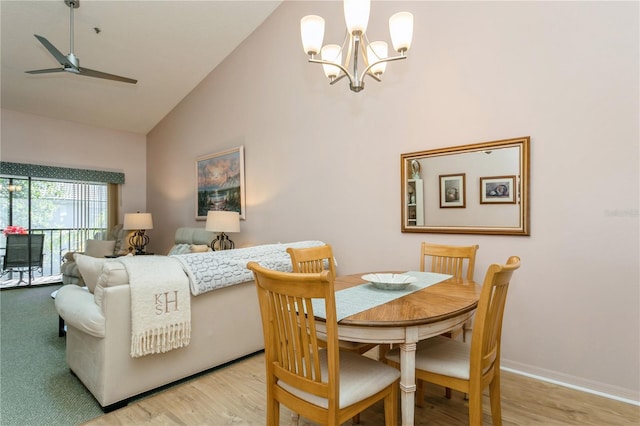 dining space with ceiling fan with notable chandelier, light hardwood / wood-style flooring, and high vaulted ceiling