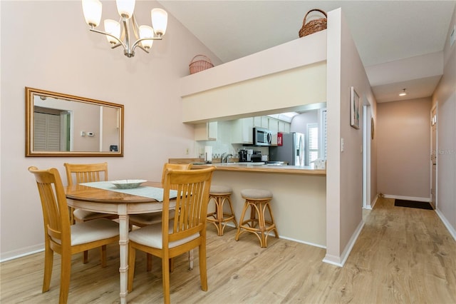 dining room featuring high vaulted ceiling, light hardwood / wood-style flooring, and a notable chandelier