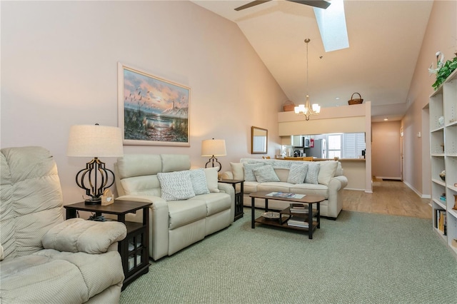 carpeted living room with a skylight, ceiling fan with notable chandelier, and high vaulted ceiling