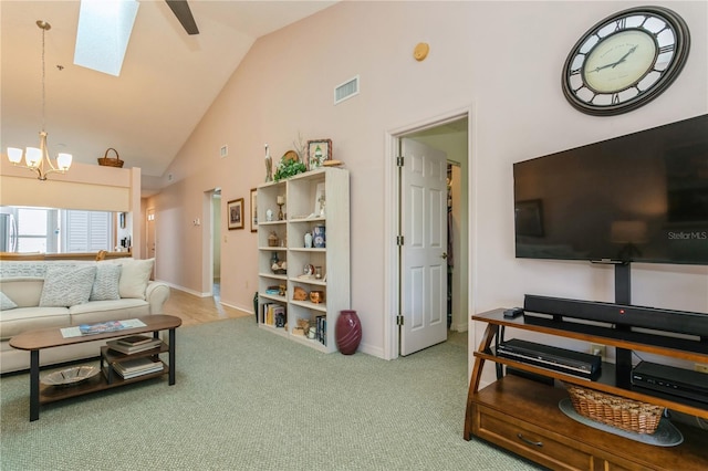 carpeted living room featuring high vaulted ceiling, a skylight, and a notable chandelier