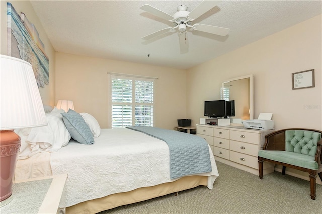 carpeted bedroom featuring ceiling fan and a textured ceiling