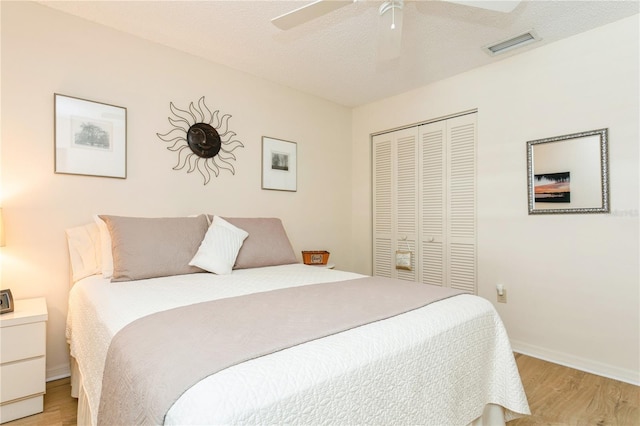 bedroom with light hardwood / wood-style floors, a textured ceiling, a closet, and ceiling fan