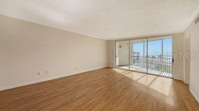 spare room featuring a wall of windows, baseboards, and wood finished floors