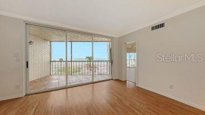 unfurnished room with visible vents, wood finished floors, and ornamental molding