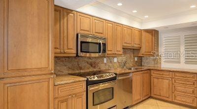 kitchen with light tile patterned floors, tasteful backsplash, stainless steel appliances, light countertops, and a sink