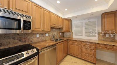 kitchen featuring appliances with stainless steel finishes, a raised ceiling, crown molding, and light tile patterned floors