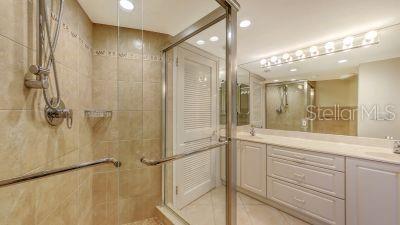 full bathroom featuring tile patterned flooring, recessed lighting, a sink, a shower stall, and double vanity