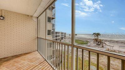 balcony with a water view and a view of the beach