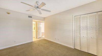 unfurnished bedroom with carpet, baseboards, ceiling fan, and a closet