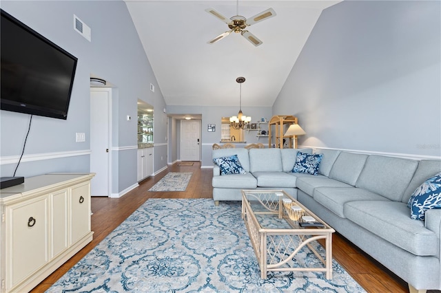 living room with ceiling fan with notable chandelier, high vaulted ceiling, and dark wood-type flooring