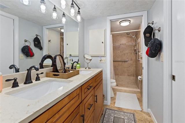 bathroom with tile patterned floors, a tile shower, vanity, a textured ceiling, and toilet