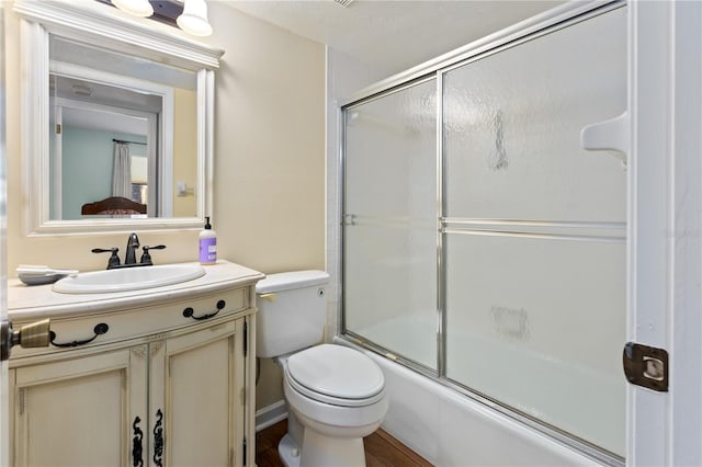 full bathroom with vanity, combined bath / shower with glass door, and toilet