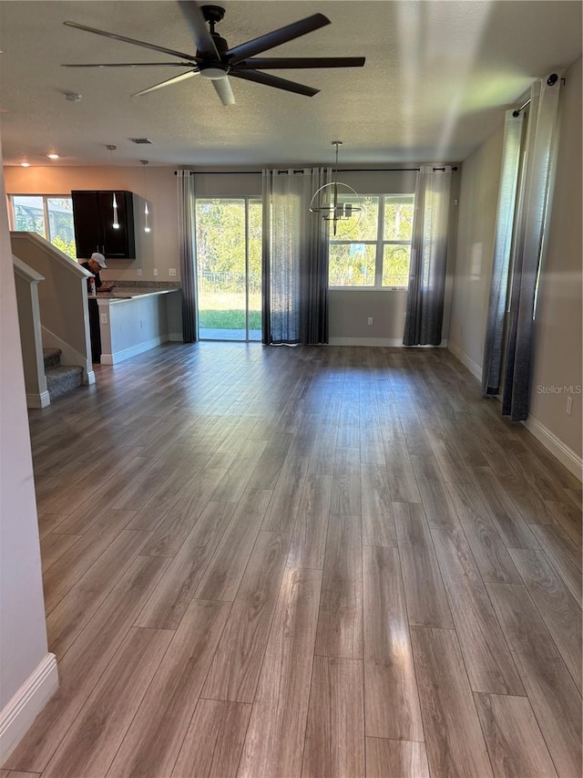 unfurnished living room with a textured ceiling, hardwood / wood-style flooring, and ceiling fan