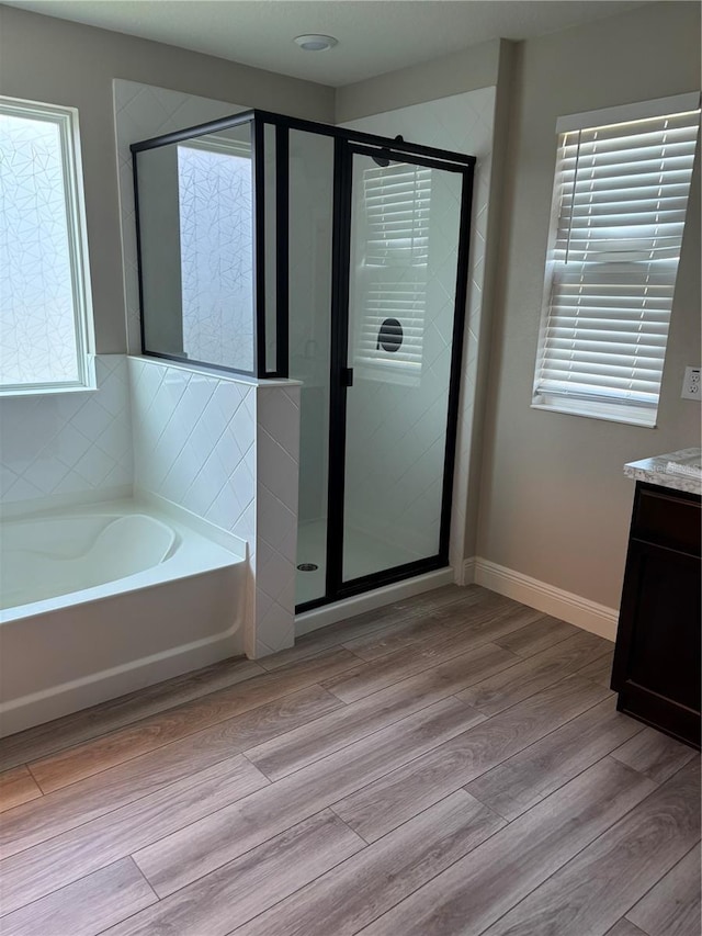 bathroom with vanity, wood-type flooring, and plus walk in shower