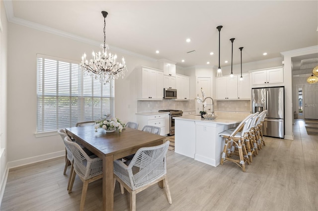 dining area with light hardwood / wood-style floors, crown molding, sink, and an inviting chandelier