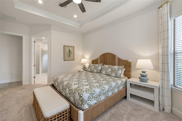 carpeted bedroom with a raised ceiling, connected bathroom, ceiling fan, and ornamental molding