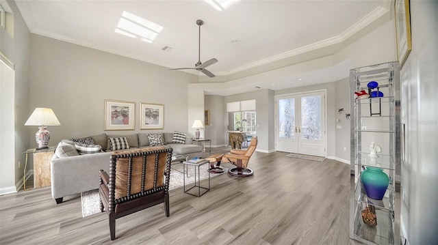 living room featuring french doors, light hardwood / wood-style flooring, ceiling fan, and crown molding