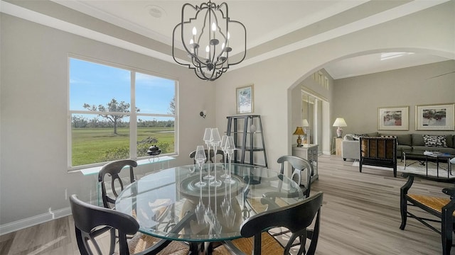 dining area with light hardwood / wood-style floors, a raised ceiling, and an inviting chandelier