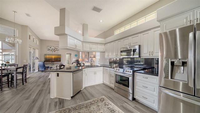 kitchen with decorative light fixtures, white cabinetry, kitchen peninsula, and appliances with stainless steel finishes