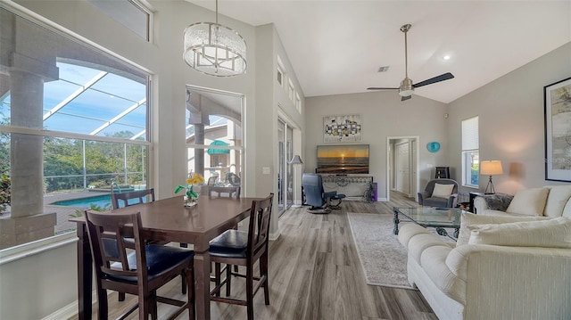 dining room featuring hardwood / wood-style floors, ceiling fan with notable chandelier, and high vaulted ceiling