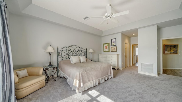 carpeted bedroom featuring a tray ceiling and ceiling fan