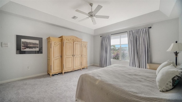 bedroom with a raised ceiling, ceiling fan, and light colored carpet